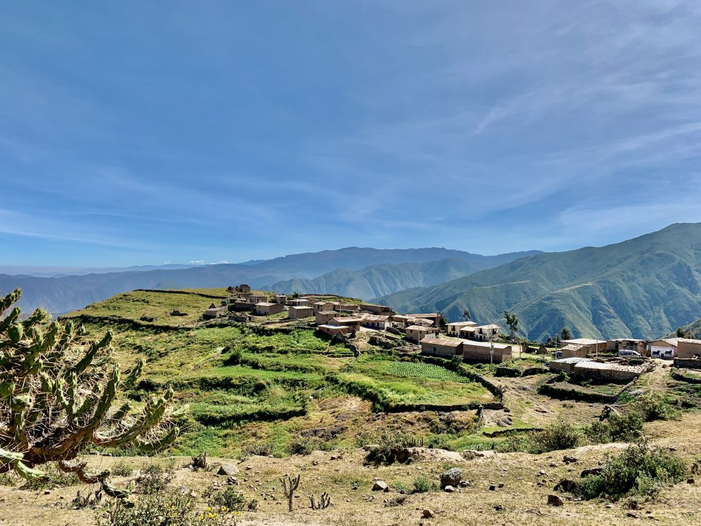 Maisemakuva korkealta vuorelta. Taustalla Andien vuoristoa, etualalla kaktus, pieniä peltotilkkuja sekä muutamia rakennusryhmittymiä.