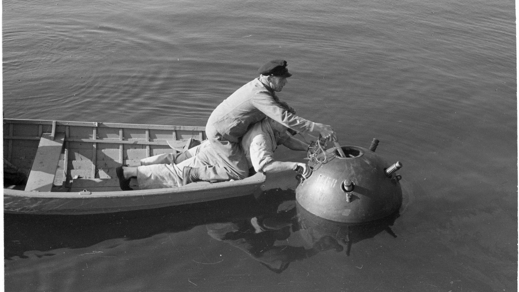 A black and white photo of two people in a row boat neutralizing sea mines in Gulf of Finland.