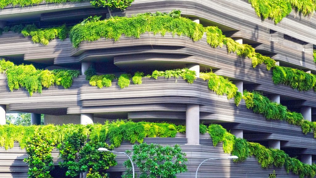 Parkkihallimainen rakennus, jonka kerroksista tulvii vihreää kasvustoa.