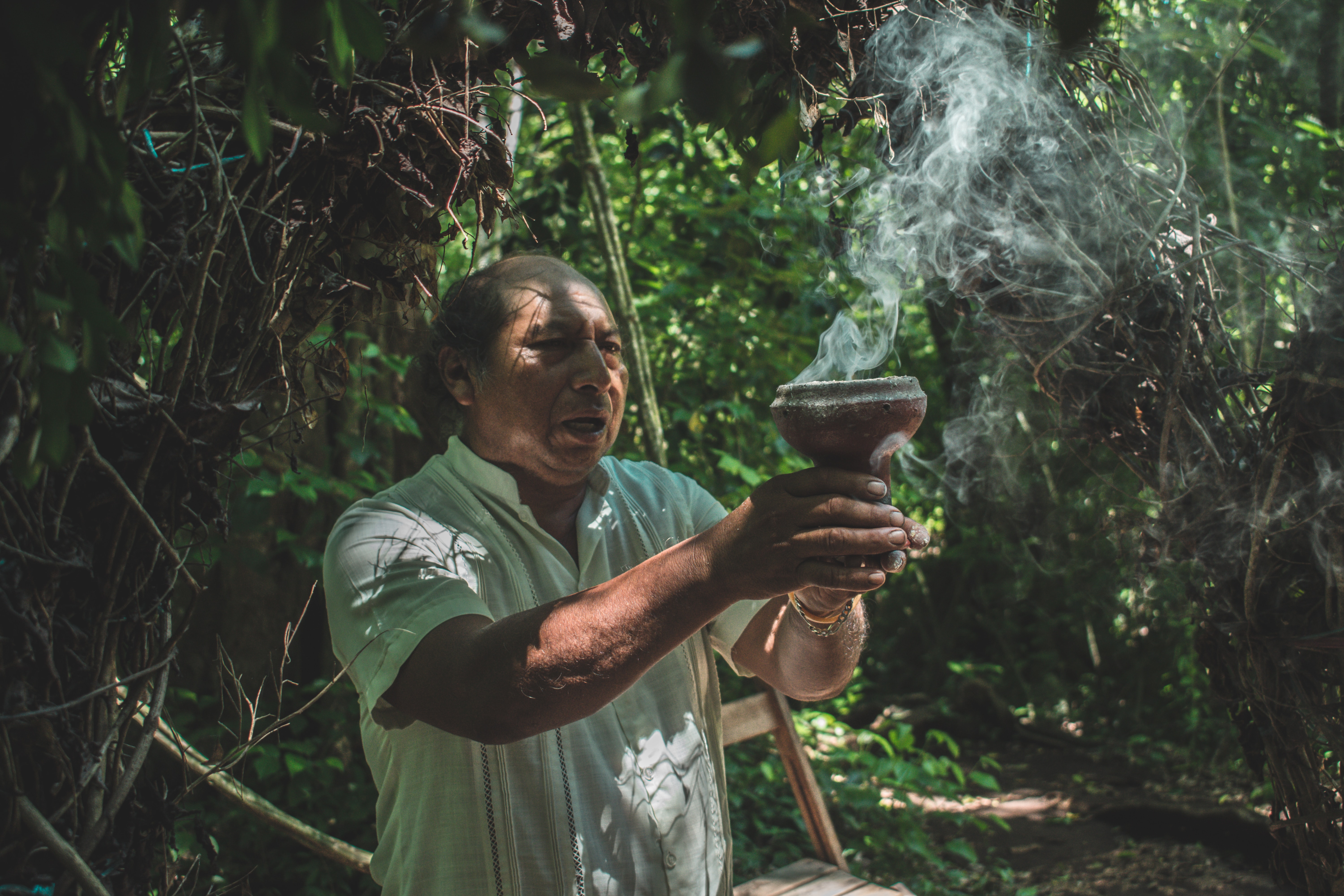 Man holding a brown pot with smoke during a Mayan ceremony in Tulum, Mexico